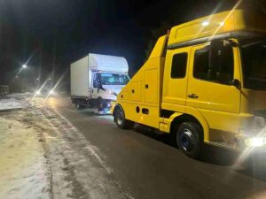 Żółta autolaweta przewożąca uszkodzony samochód osobowy po kolizji w Piotrkowie Trybunalskim.